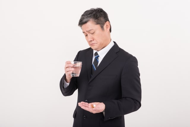 薬を飲む男性